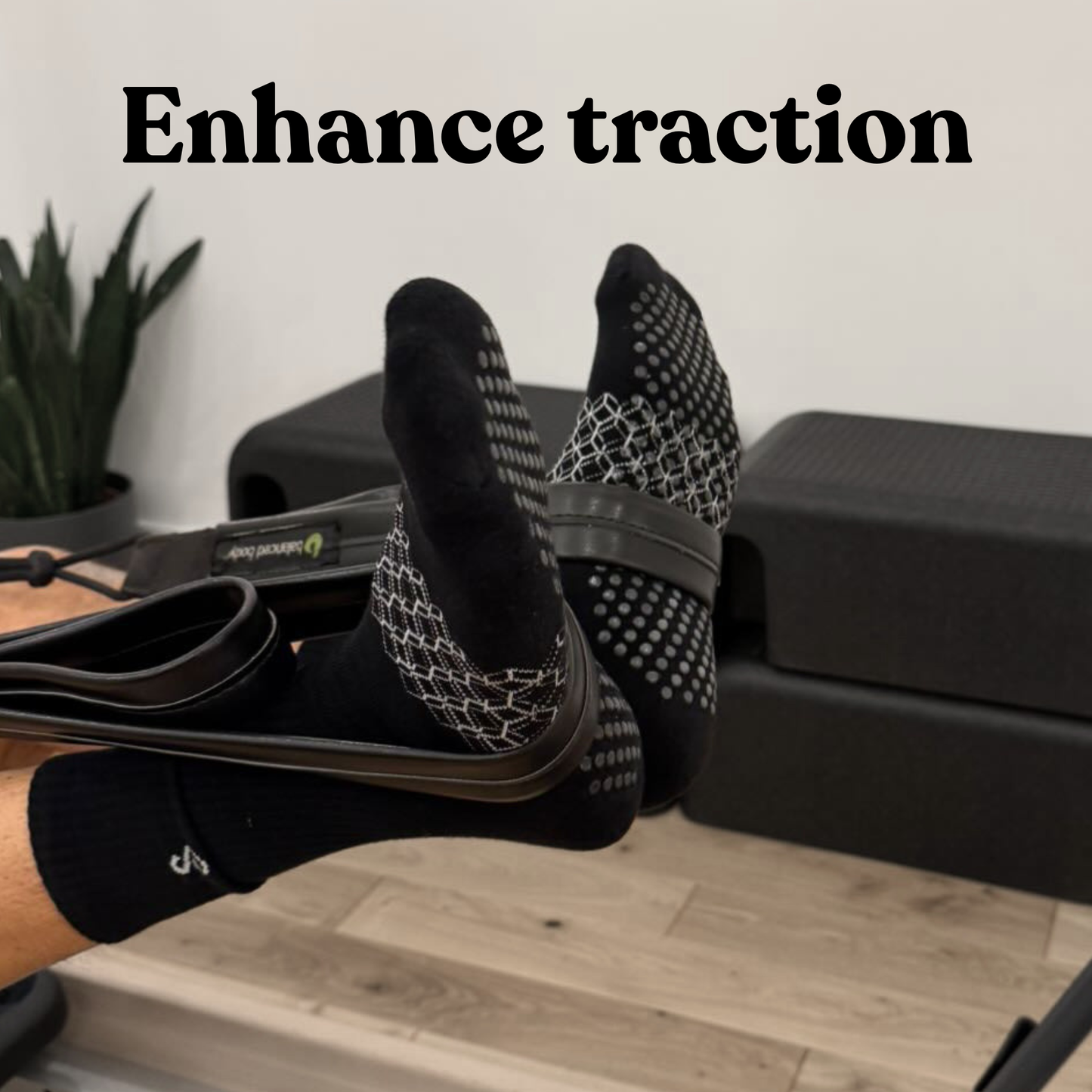 Flow crew black grip socks by hipSwan shown on a person's feet during a Pilates reformer session with the text 'Enhance traction' at the top.