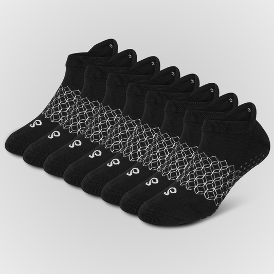 Eight black hipSwan Flow Ankle low-cut ankle grip socks arranged in a fan shape on a light gray background. Each sock features a white geometric honeycomb pattern around the ankle area and a small white logo near the toe.